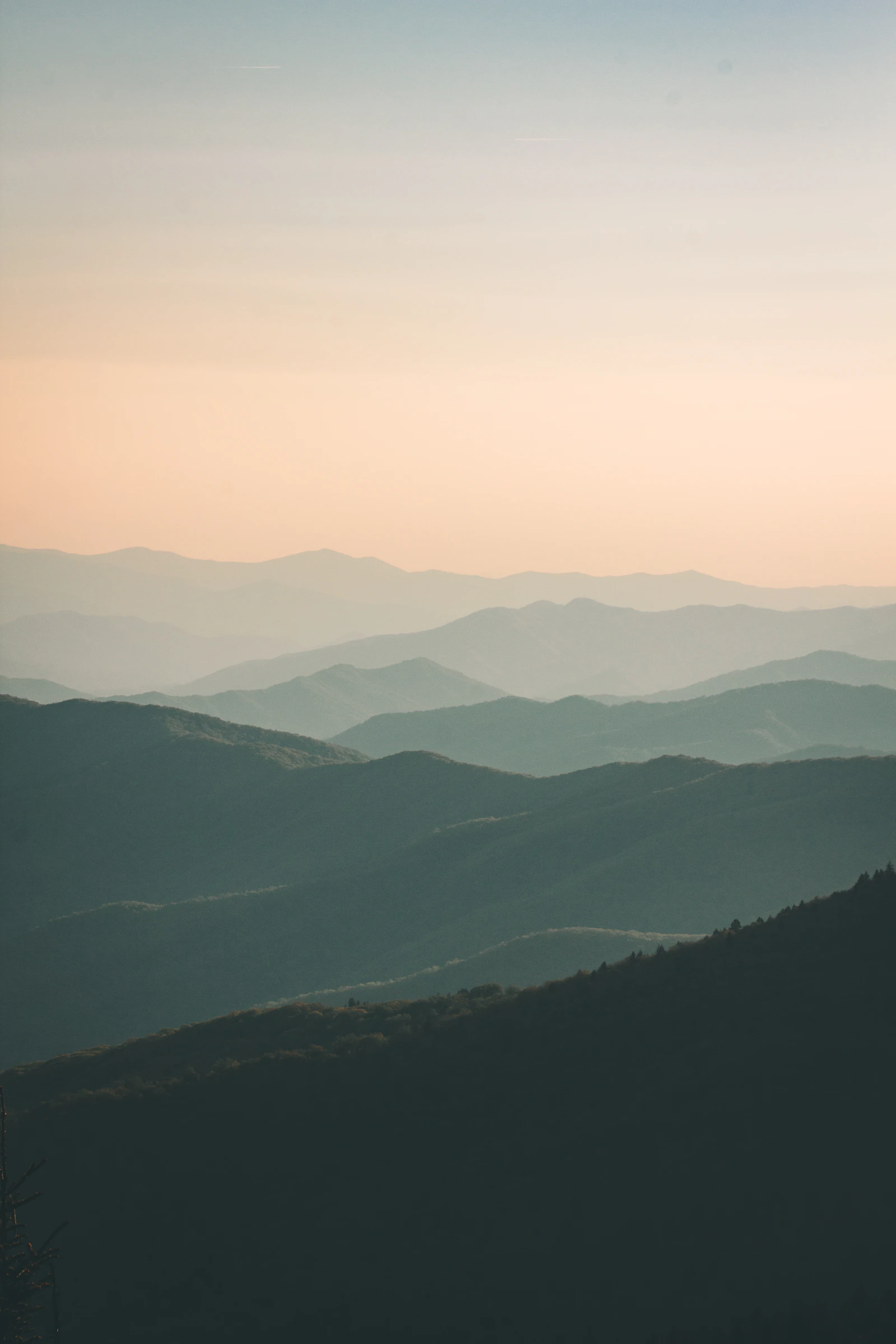 Layered mountain ridges fading into warm evening haze