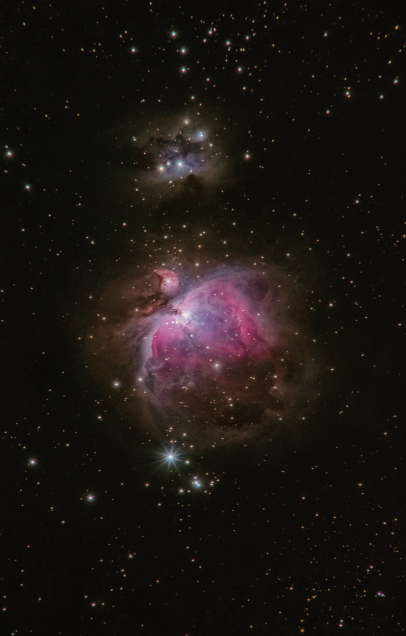 The Orion Nebula glowing pink and purple among dense star fields